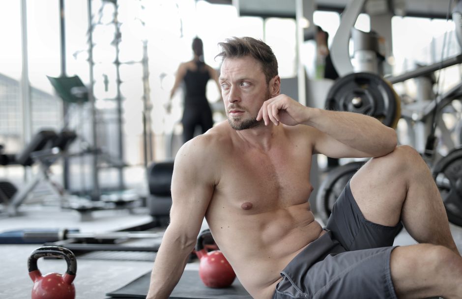 A muscular man taking a break in a modern gym after an intense workout session. A muscular man taking a break in a modern gym after an intense workout session.