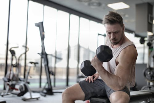 Free Man in White Tank Top and Grey Shorts Lifting Dumbbell Stock Photo