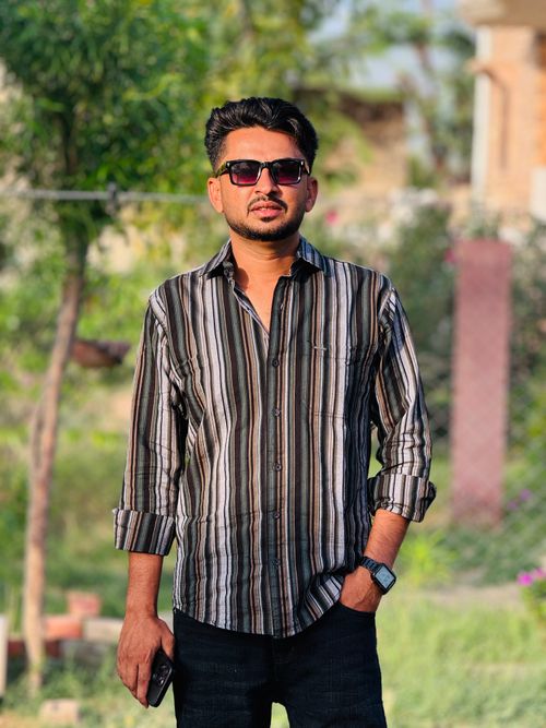 Free Young man outdoors in sunglasses with a casual striped shirt. Bright day. Stock Photo