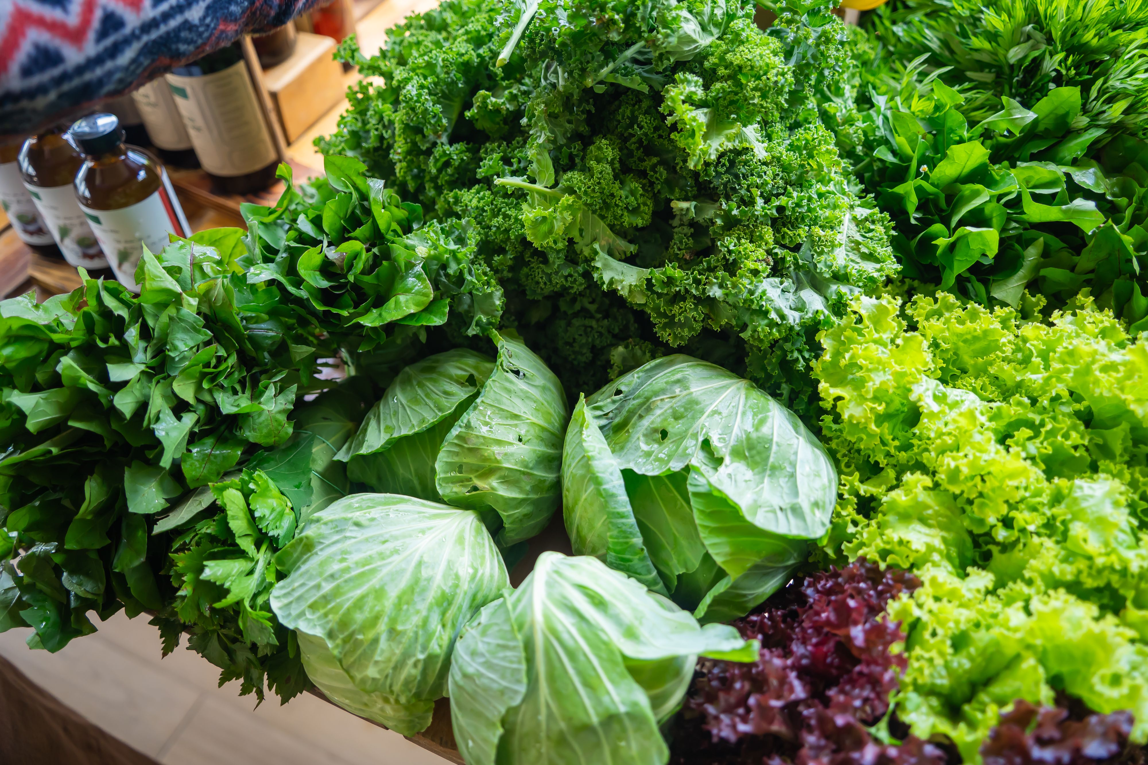 A vibrant display of assorted leafy greens including cabbage, kale, and lettuce at a market.