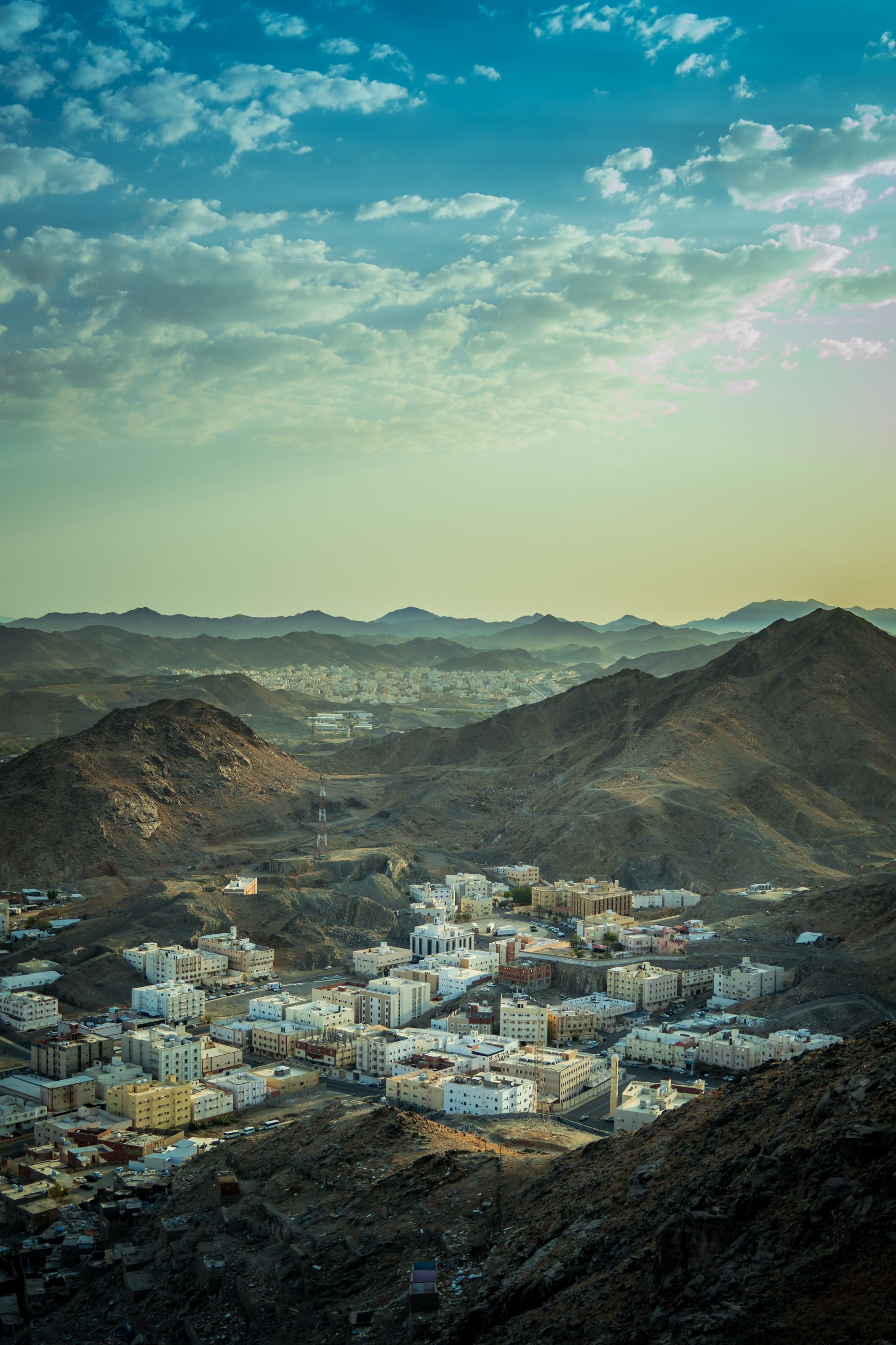 Captivating aerial view of Makkah city surrounded by mountains under a vibrant sky.