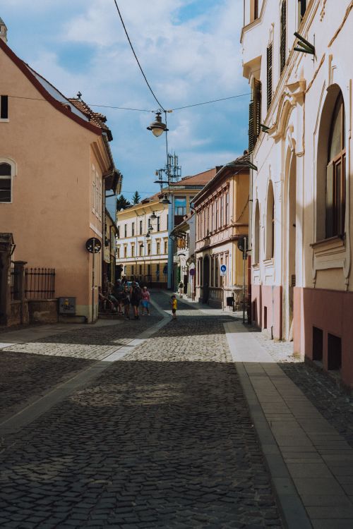 Free Discover a quaint cobblestone street lined with historic buildings in a charming Romanian town. Perfect for travel inspiration. Stock Photo
