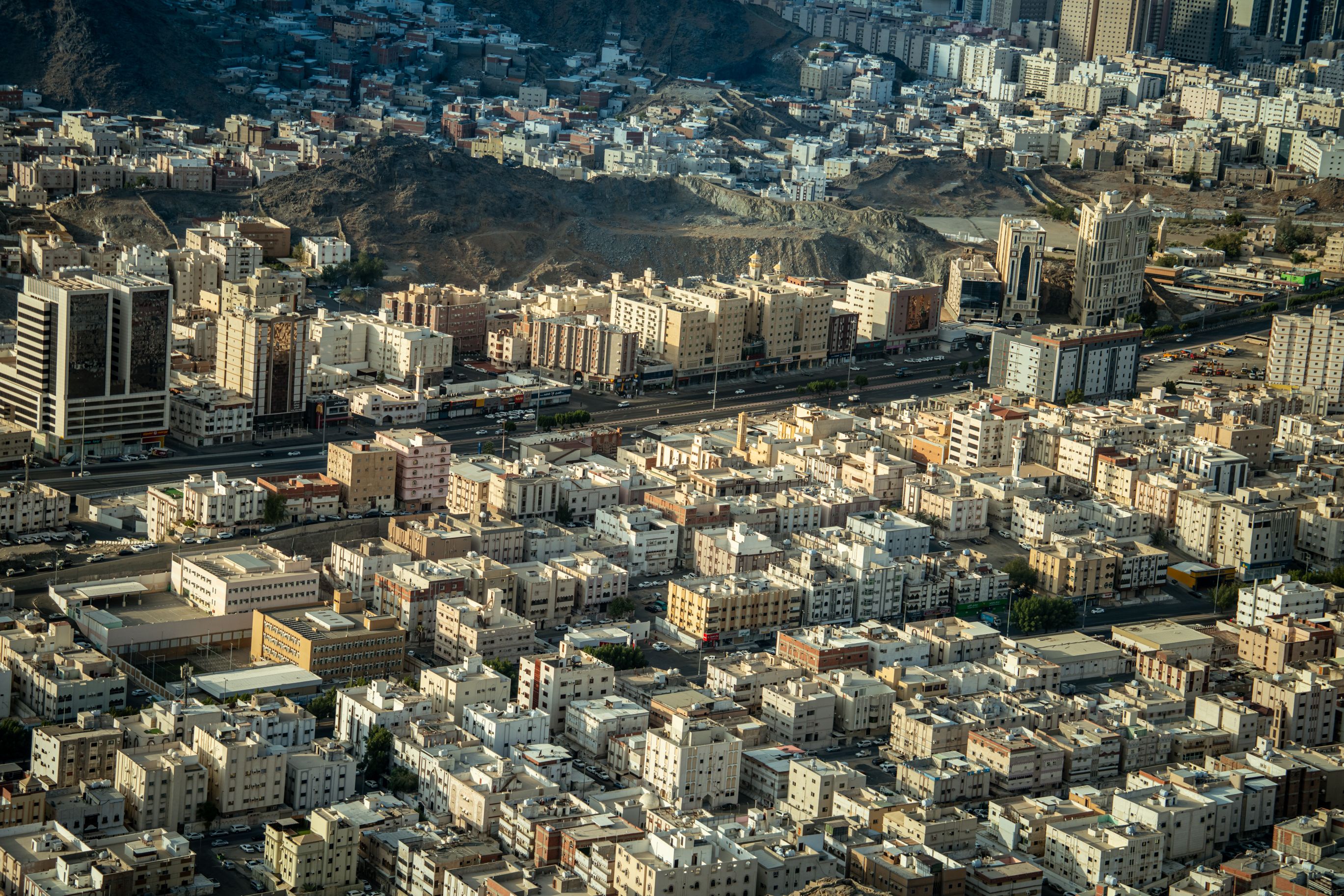 Aerial shot of Makkah city showing urban buildings and mountainous landscape.