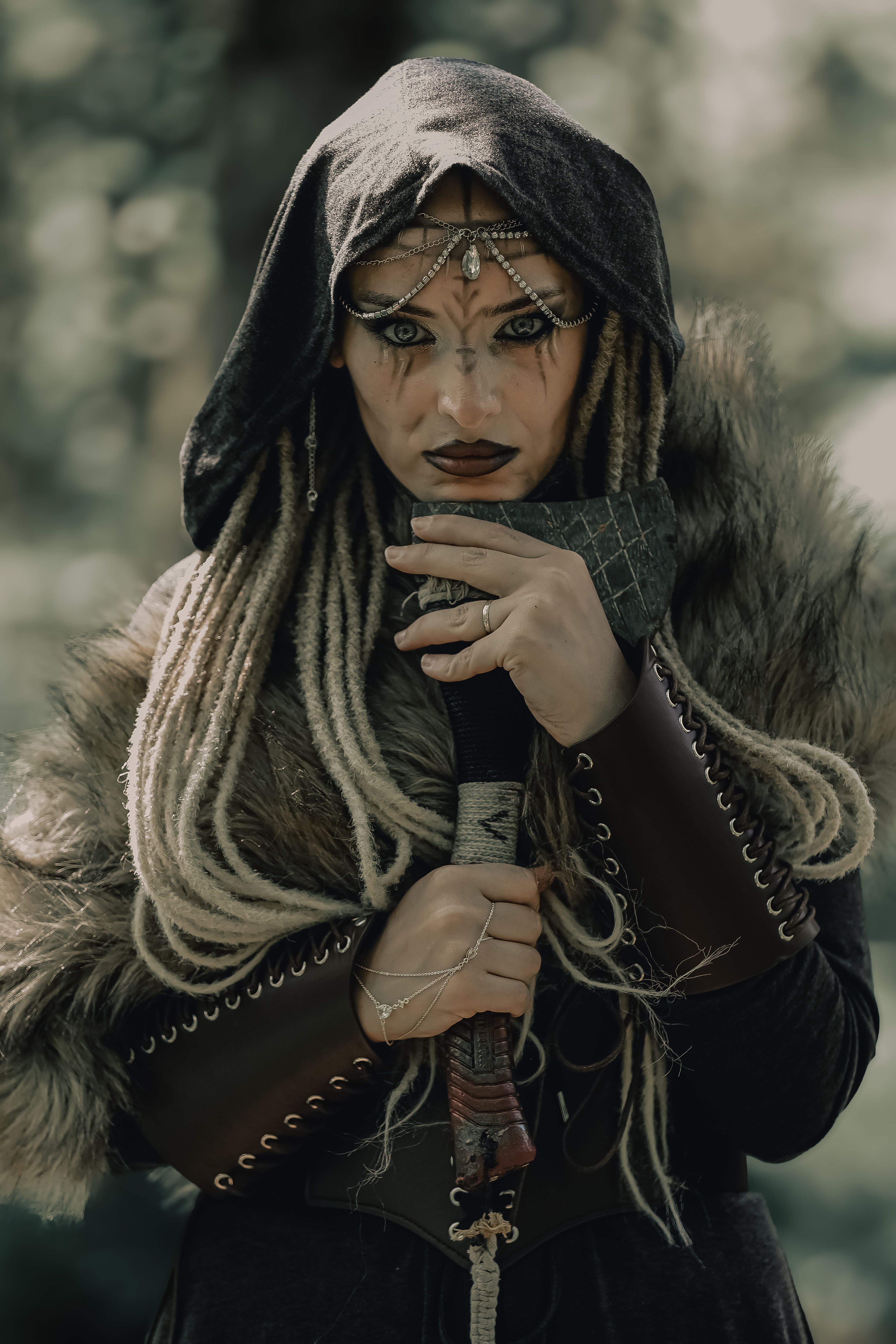 A warrior dressed in tribal attire with intricate adornments stands in a forest, exuding mystery and strength.