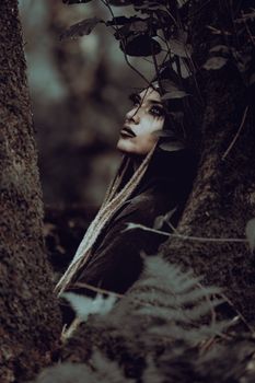 Artistic portrait of a woman in a mystical forest setting with a dramatic mood.
