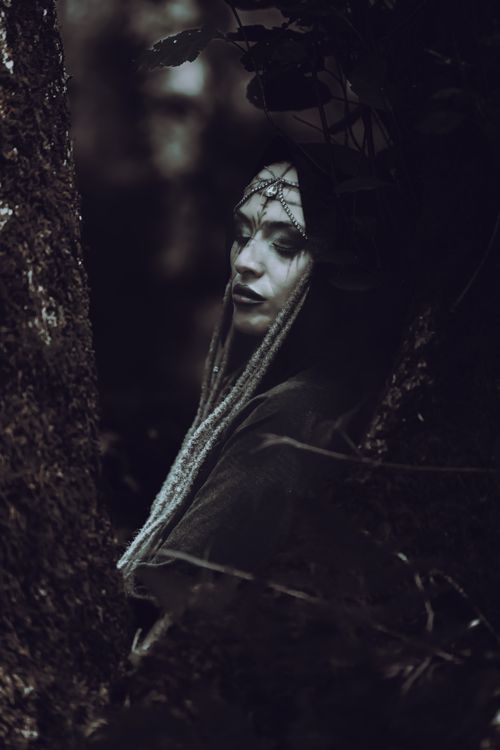 Free Mysterious woman with decorative headpiece in a dark, moody forest scene, evoking fantasy themes. Stock Photo