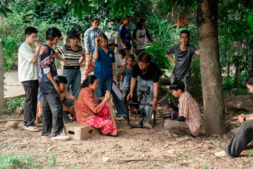 Free Filmmakers and crew collaborate on outdoor movie set under trees. Stock Photo