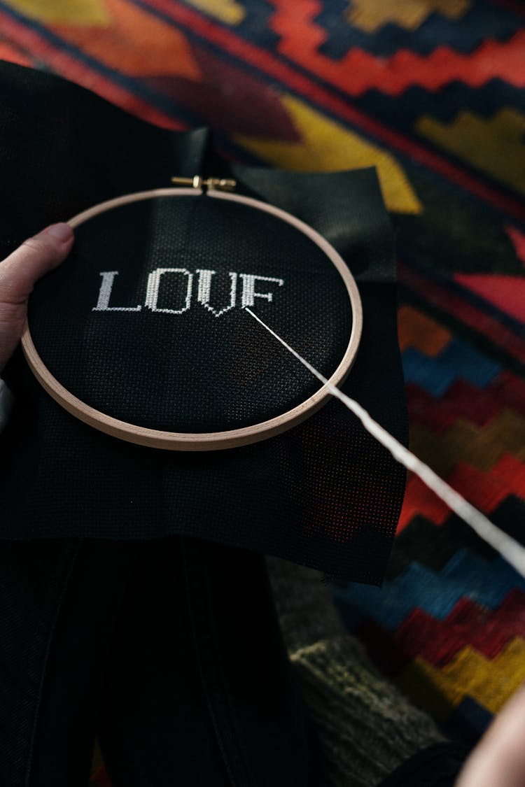 Close Up Of A Person Embroidering The Word Love On Black Fabric