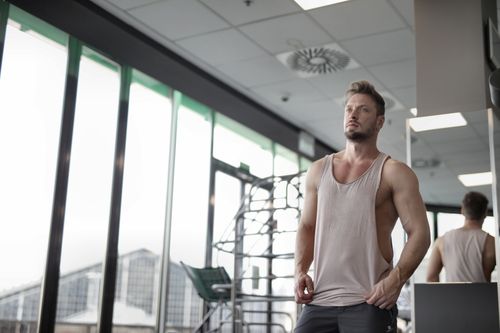 Free A fit and muscular man posing in a gym with floor-to-ceiling windows. Perfect for fitness and lifestyle themes. Stock Photo