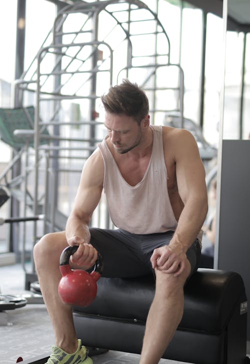 Free Man In White Tank Top Lifting Kettlebell Stock Photo