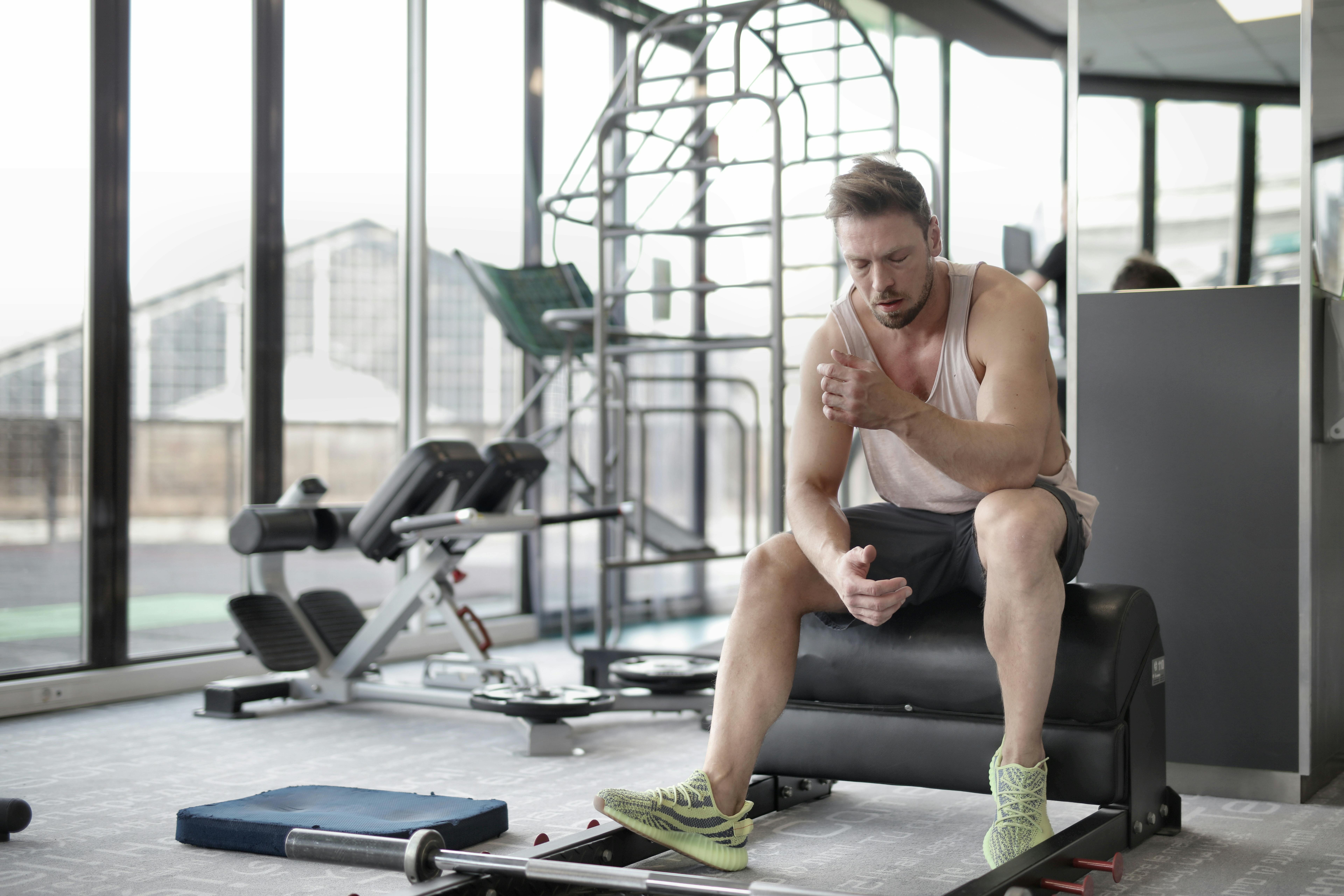 Serious young male athlete resting after workout in modern fitness