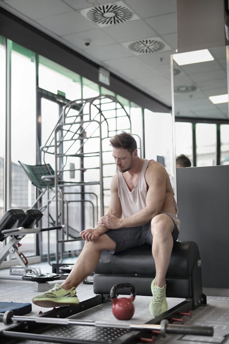 Tired Male Athlete Resting On Bench During Weightlifting Workout In Gym