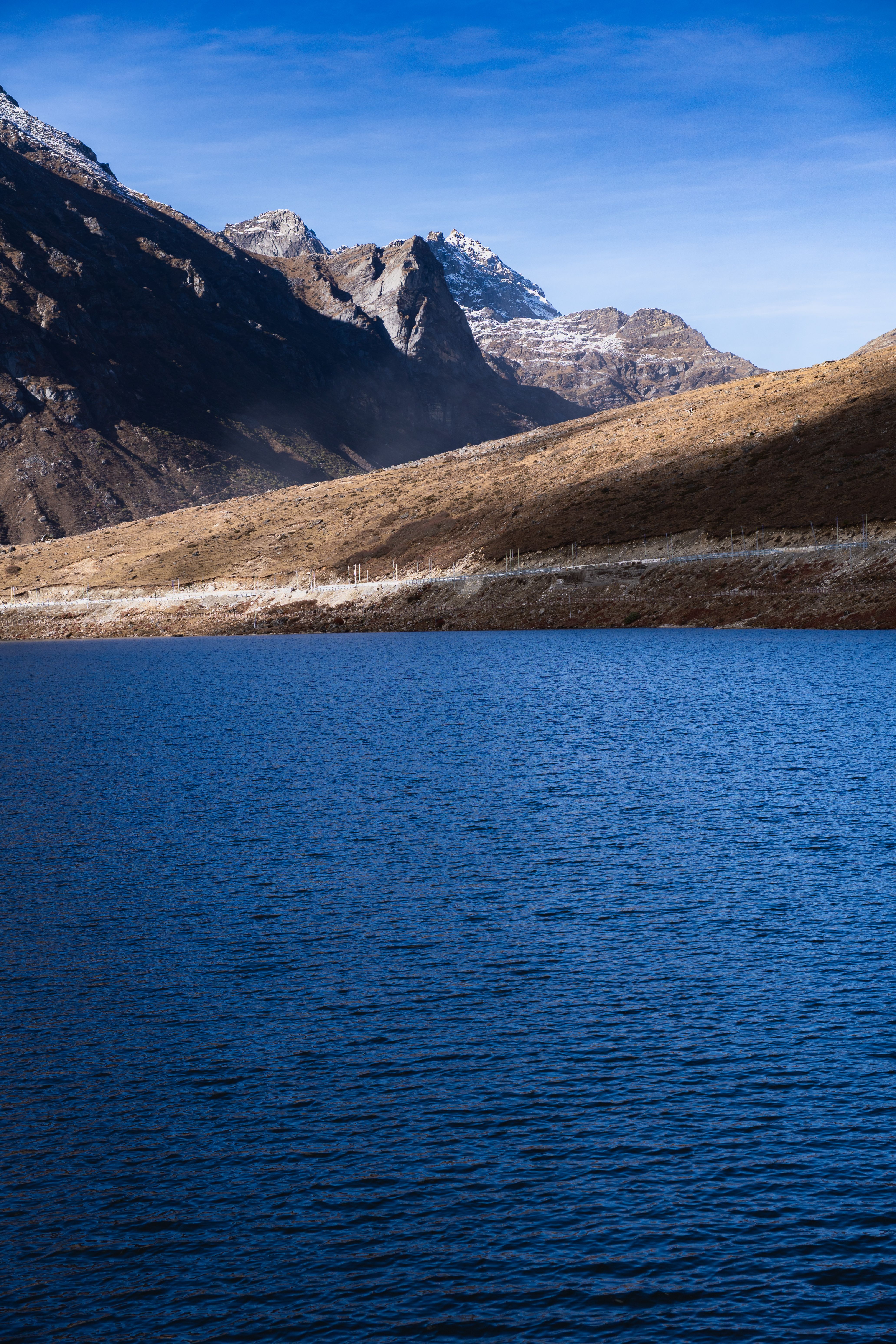 Stunning view of a tranquil lake surrounded by rugged mountains under a clear blue sky in Arunachal Pradesh, India.