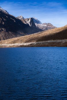 Stunning view of a tranquil lake surrounded by rugged mountains under a clear blue sky in Arunachal Pradesh, India.