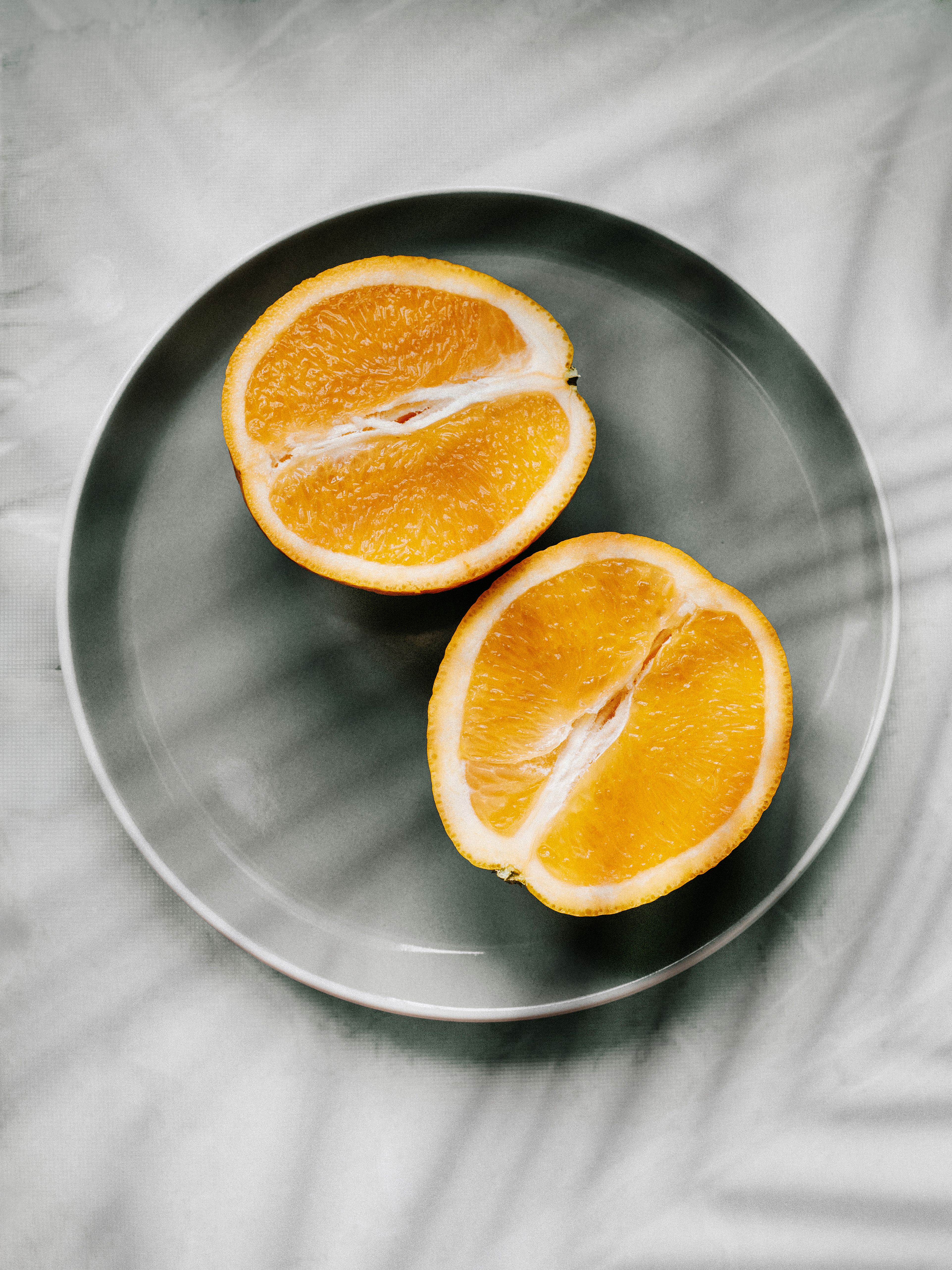 Vibrant orange halves neatly placed on a plate, showcasing freshness and vitality.