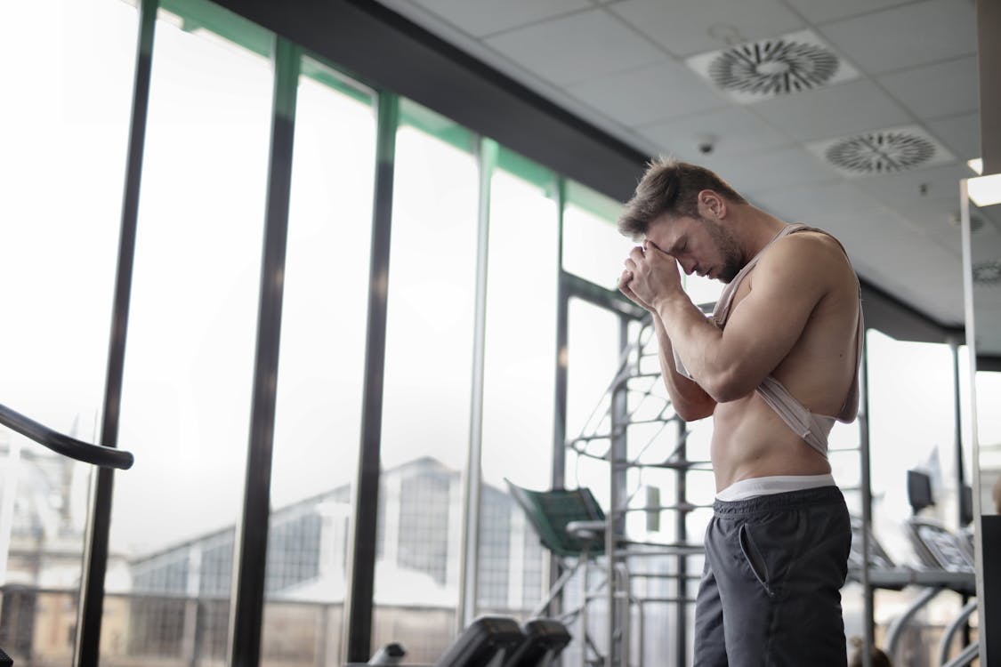 Free Sweaty tired muscular sportsman resting after workout in gym Stock Photo