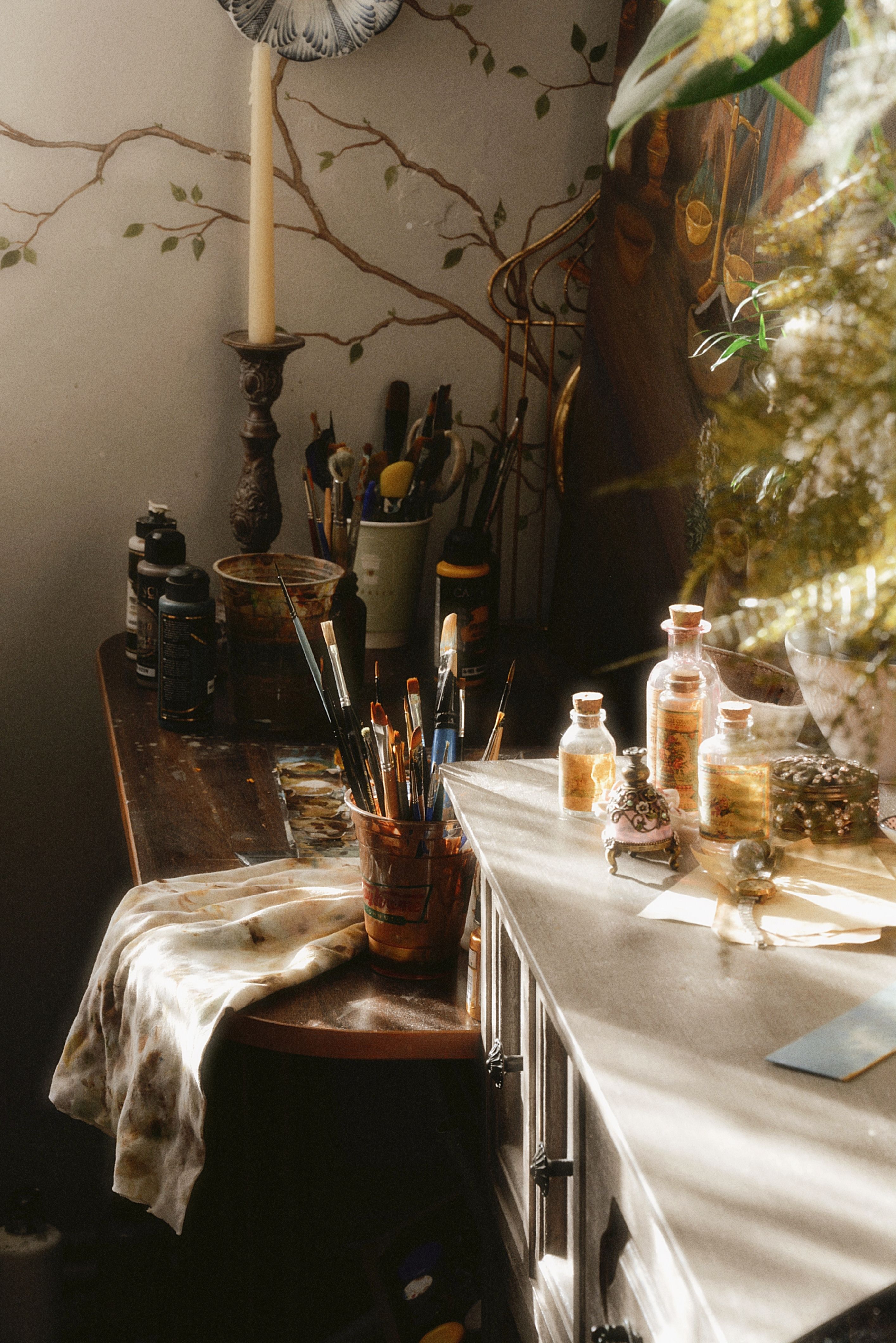 Artistic workspace with brushes, paints, and warm sunlight creating a cozy atmosphere.