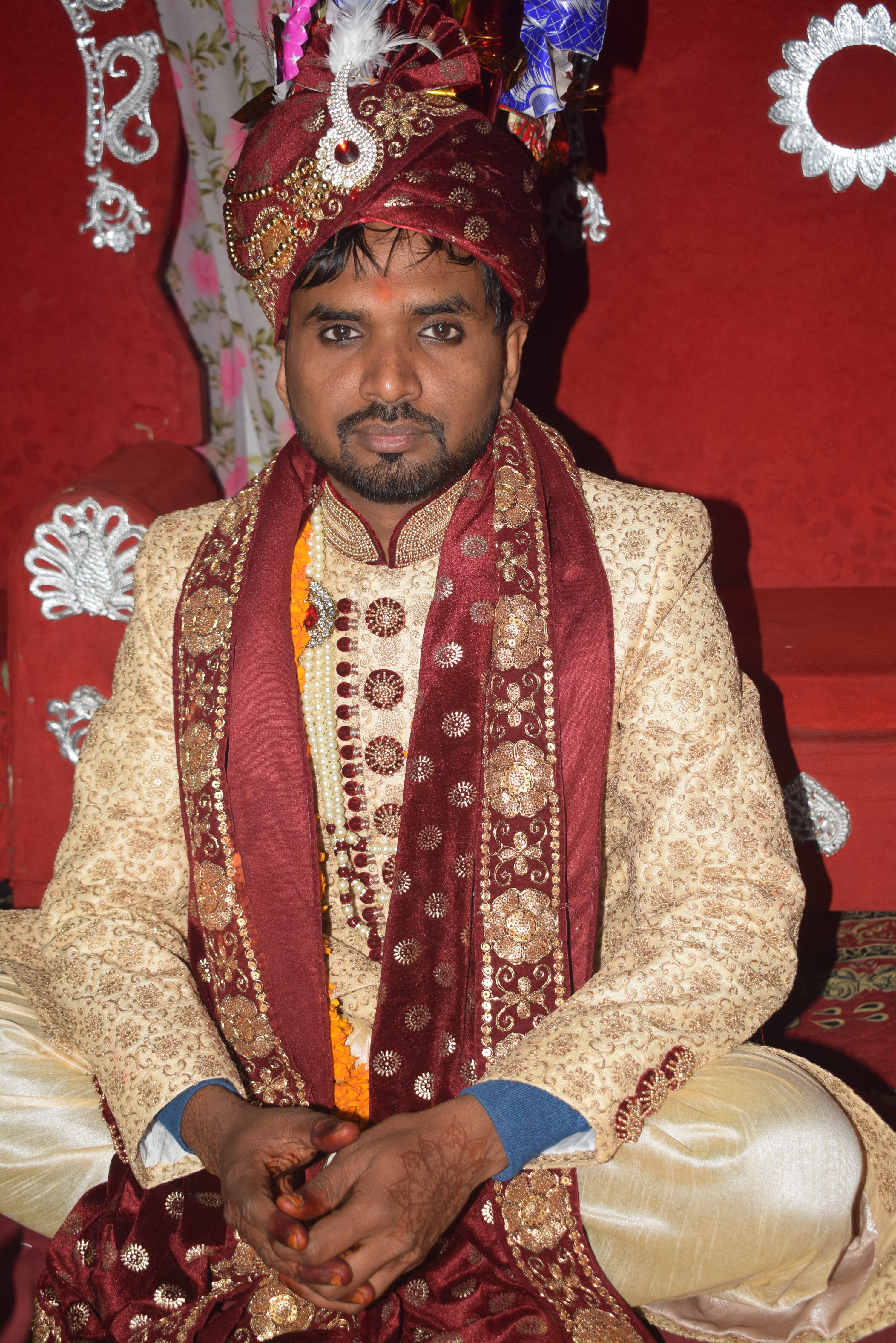 Close-up of a man in ornate traditional wedding attire, showcasing rich embroidery and vibrant colors.