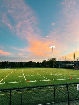 Empty football field under a vibrant sunset sky providing ample copyspace.