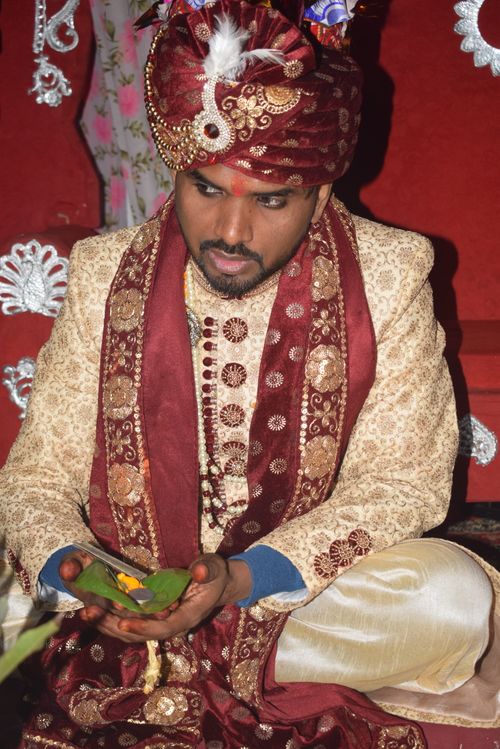 Free Groom in traditional attire during a South Asian wedding ritual indoors. Stock Photo