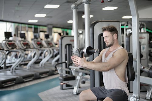 Serious sportsman training on exercise machine in modern gym