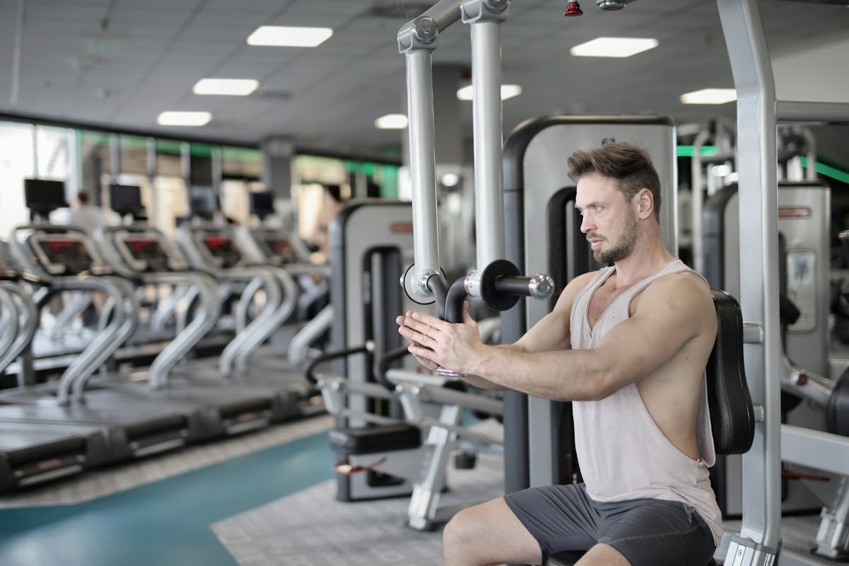 Young man lifting weights while staring intensely at his reflection in the gym mirror