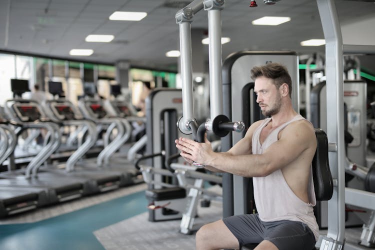 Serious Sportsman Training On Exercise Machine In Modern Gym