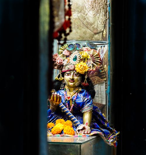 Free A colorful statue of a Hindu deity adorned with floral headdress and traditional attire, captured in a shrine. Stock Photo