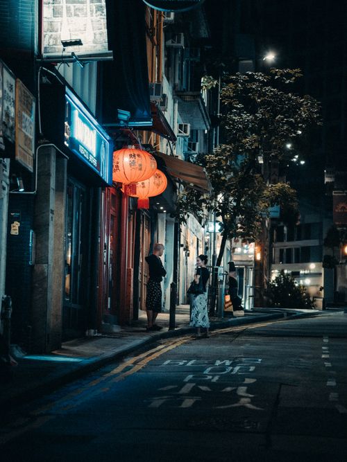Free A nighttime street view with people walking near shops and red lanterns in a city. Stock Photo