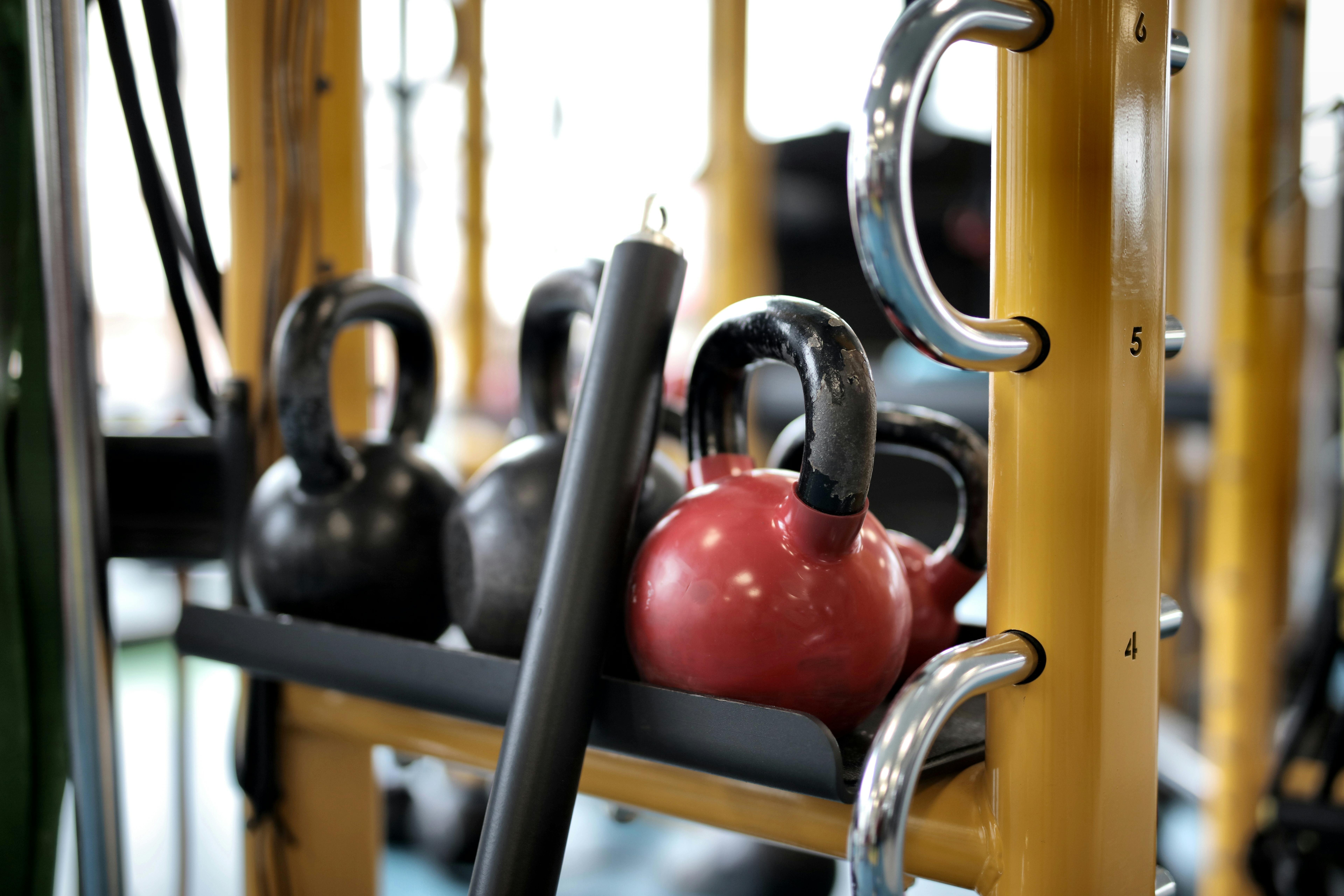 several kettlebells on metal bar in gym