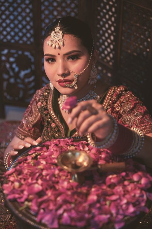 Free Beautiful portrait of a woman in traditional Indian bridal attire holding rose petals. Stock Photo