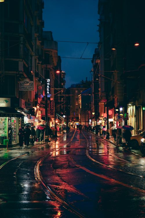 Free Crowded urban street at night showcasing vibrant lights and reflections on wet pavement. Stock Photo