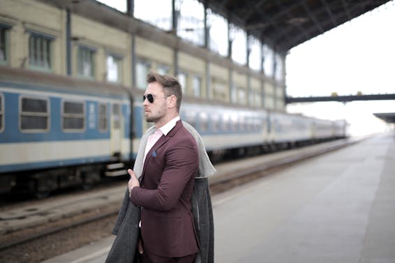 Confident stylish passenger standing on railway station and waiting for departure