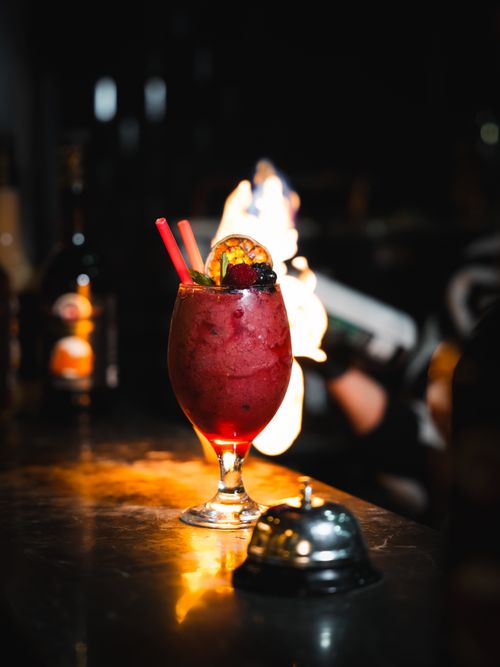 Free A striking berry cocktail garnished with fruit served in a dimly lit bar setting, capturing a glamorous atmosphere. Stock Photo