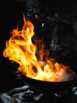 An intense close-up of vibrant orange flames rising from a wok during stir fry cooking.