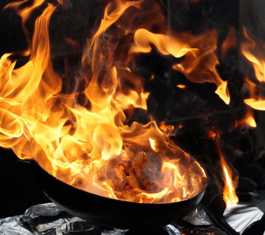 Fiery wok cooking with vibrant flames enhancing a dynamic culinary scene.