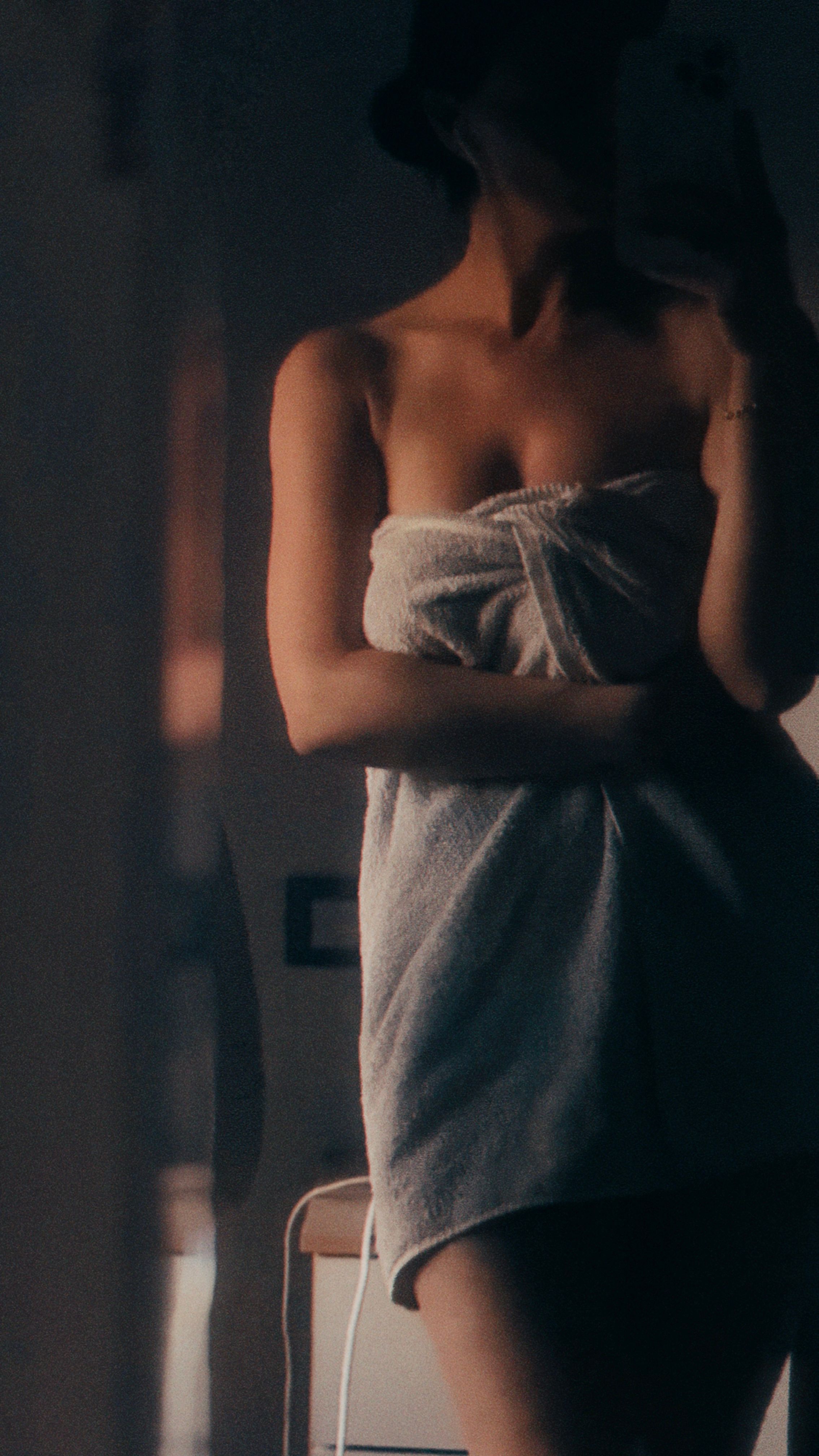 A silhouette of a woman wrapped in a towel, captured in a warm, reflective atmosphere.