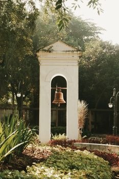 A picturesque view of a historic bell in a lush garden in Bandung, Indonesia.
