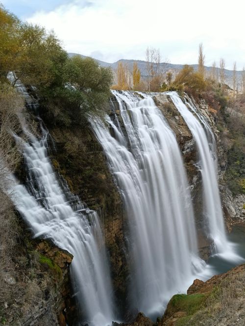 Free Discover the serenity of a stunning waterfall flowing over rugged rocks, captured during a serene day. Stock Photo