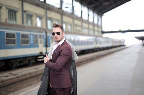 Man in Maroon Suit and black eyeglasses Standing on Sidewalk