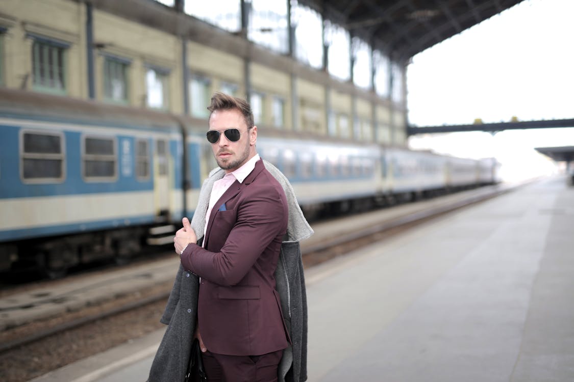 Man in Maroon Suit and black eyeglasses Standing on Sidewalk