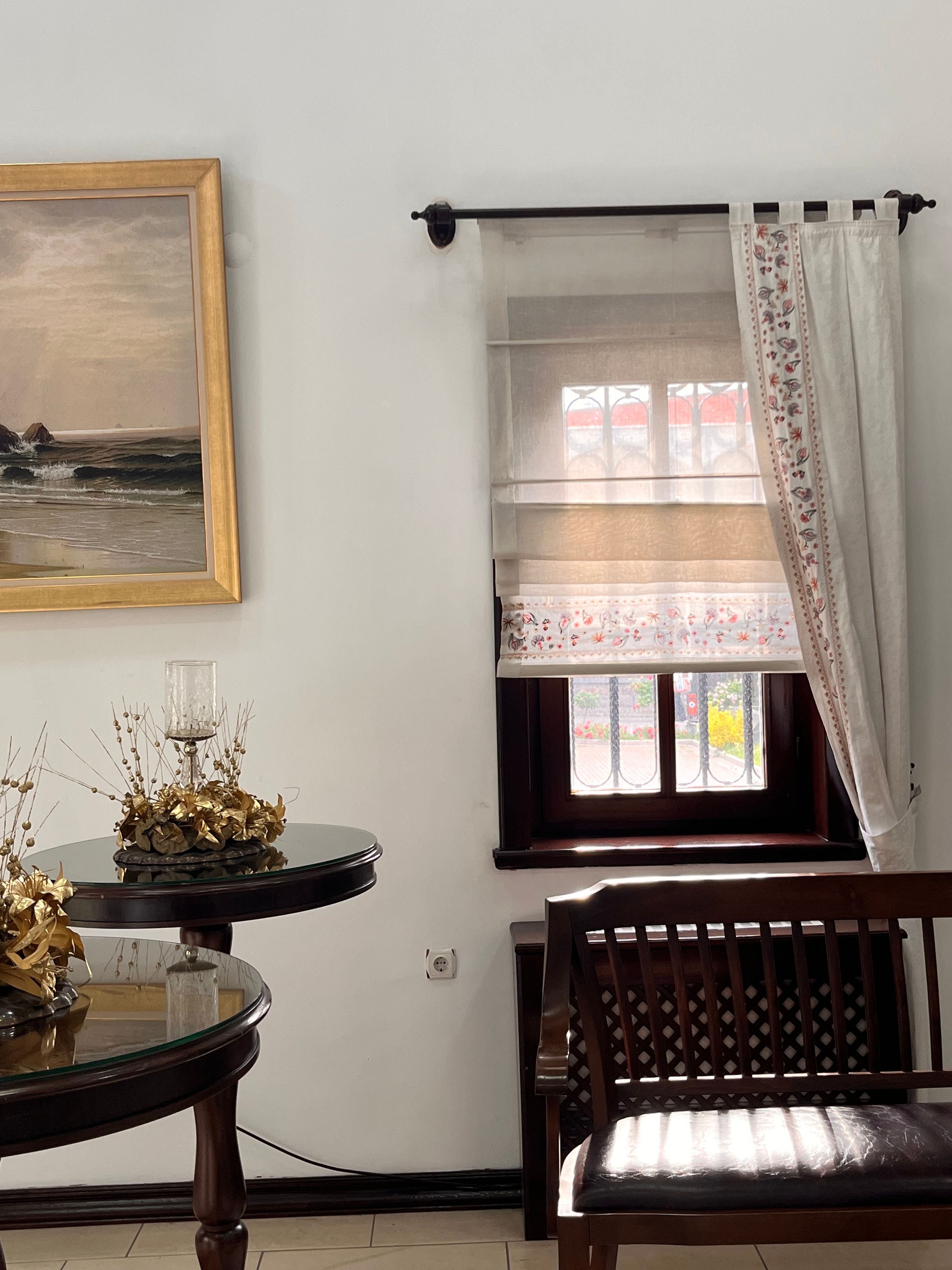 Sophisticated living room with wooden furniture and decorative window treatments, exuding elegance and warmth.