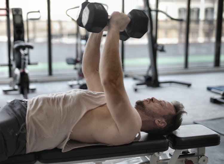 Man In White Tank Top And Grey Shorts Lifting Weights