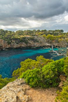 Explore Cala Pi's breathtaking cliffs and vibrant waters on a cloudy day.