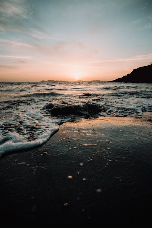 無料 日没時に岸に打ち寄せる海の波 写真素材