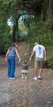 A family enjoying a walk in a lush forest during the day with their child.