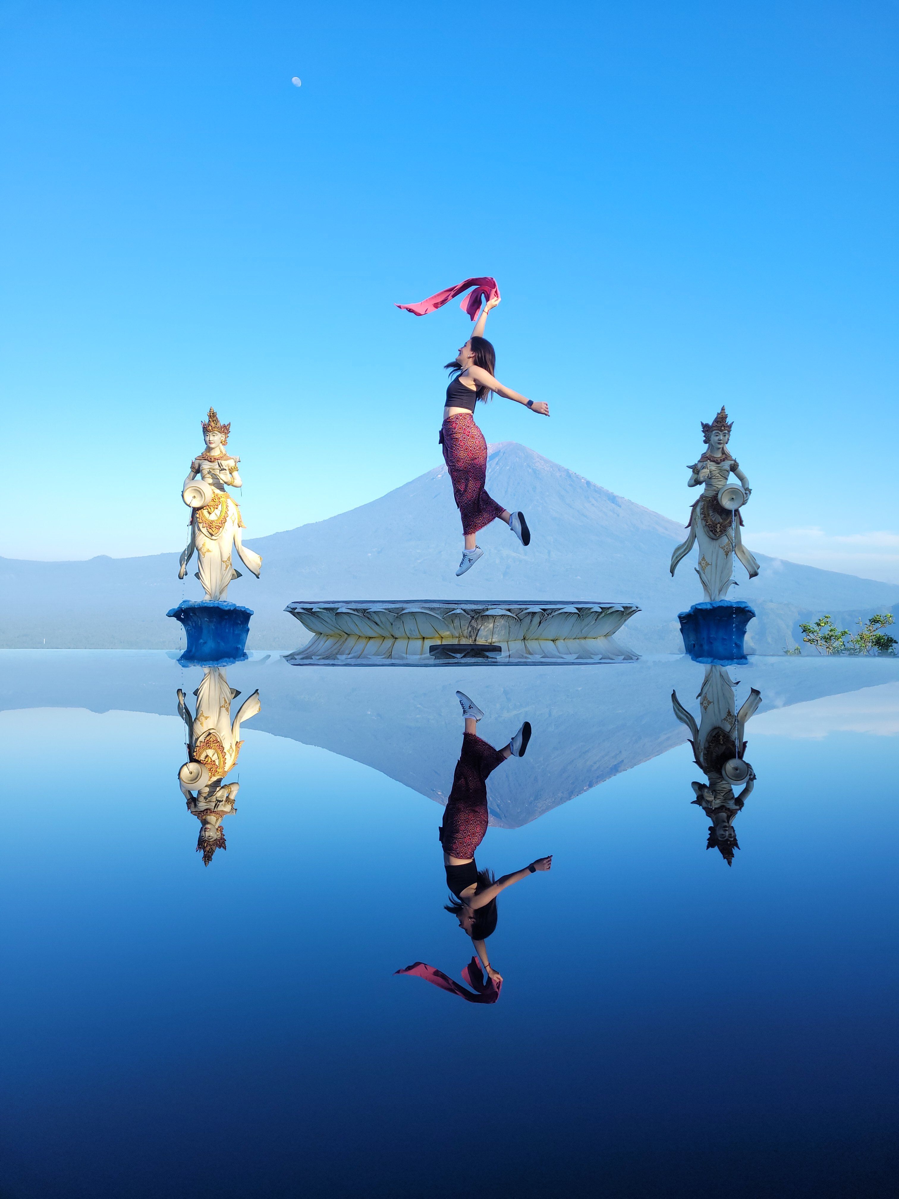 A Balinese dancer leaps in front of Mount Agung with stunning water reflection.