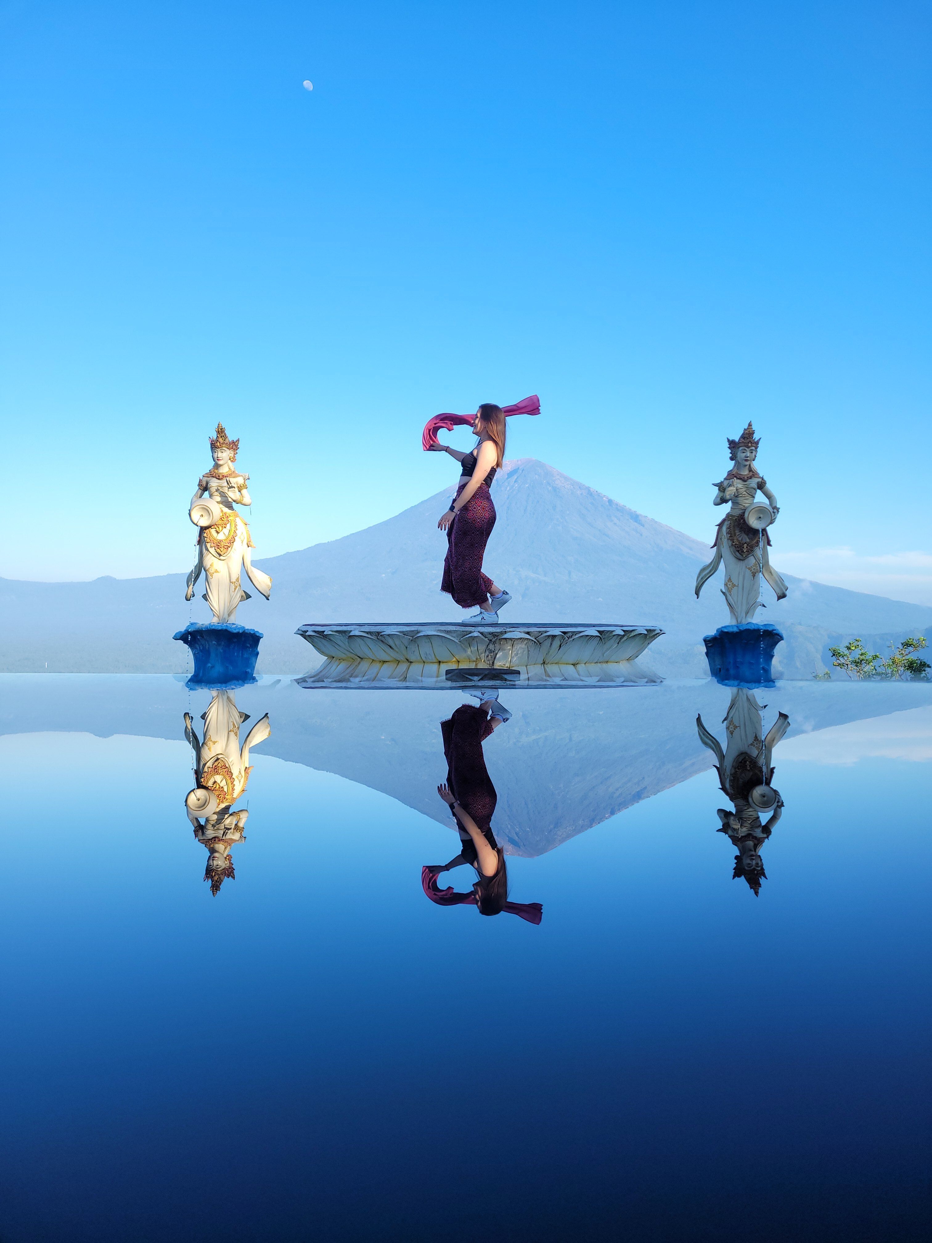 Stunning view of statues and reflection in a pool against Mount Agung in Bali, Indonesia.