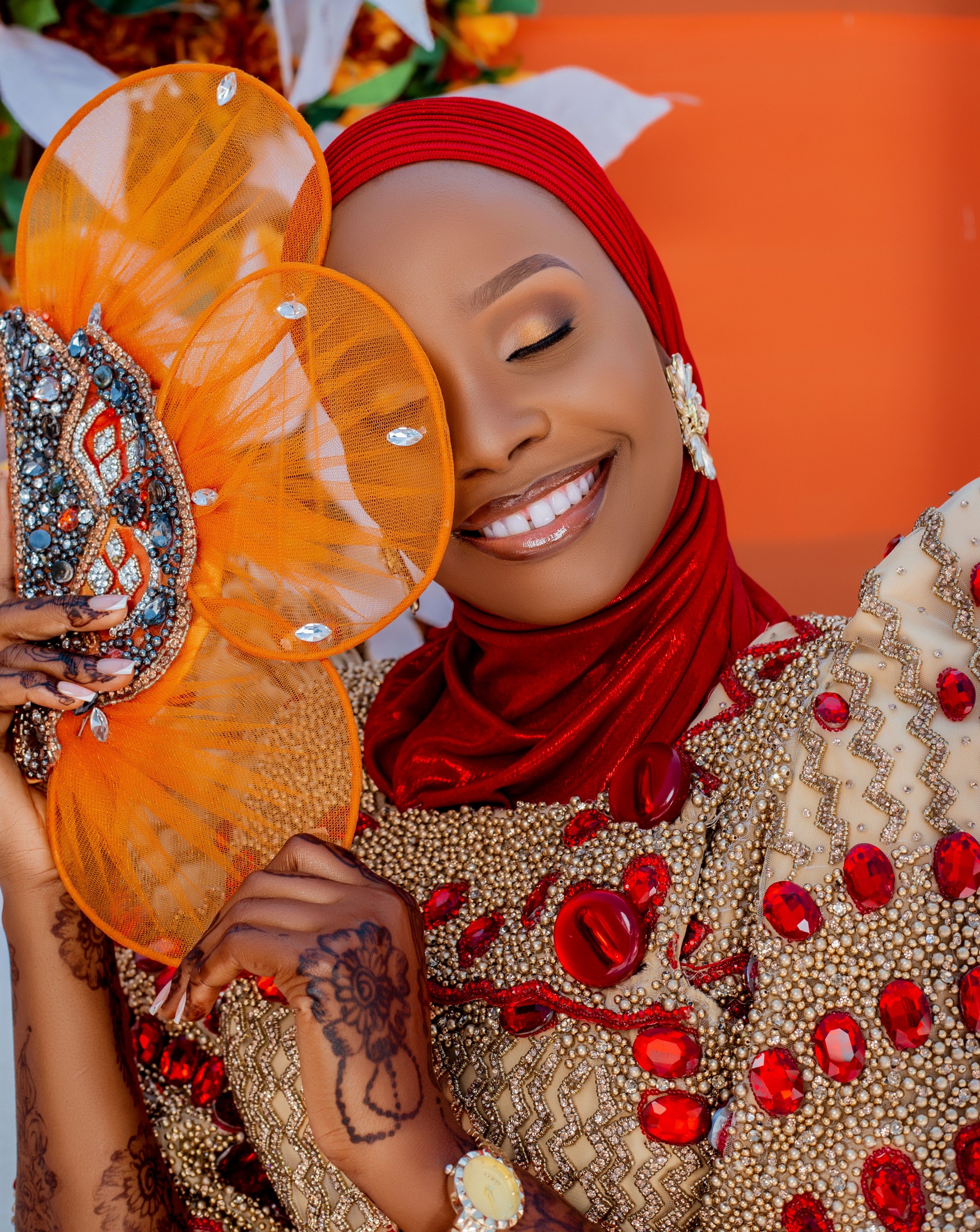 Beautiful woman wearing vibrant traditional attire with decorative fan, smiling joyfully.