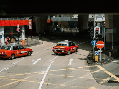 From above of red taxi cars driving on asphalt street near crossroad in modern city district on sunny day